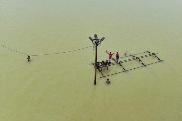 Unas personas juegan sobre una estructura sumergida en Daraganj Ghat, una de las orillas inundadas del río Ganges en Allahabad (la India) el 8 de agosto. - Sputnik Mundo