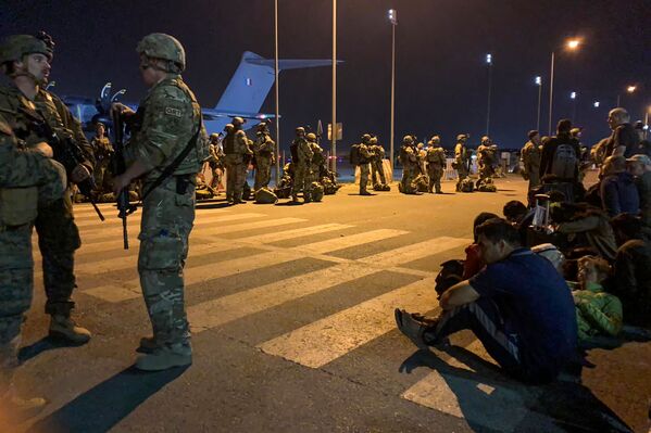 Soldados franceses hacen guardia mientras ciudadanos de Francia y sus colegas afganos esperan para subir a un avión de transporte militar en el aeropuerto de Kabul, el 17 de agosto de 2021. - Sputnik Mundo