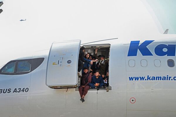 Varios afganos se encaraman a un avión con la esperanza de poder salir de su país. - Sputnik Mundo