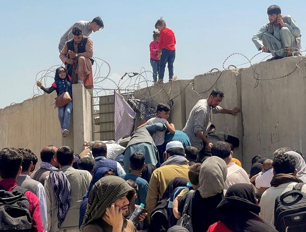 Un hombre agarra a una chica para entrar en el aeropuerto internacional Hamid Karzai en Kabul, Afganistán, el 16 de agosto de 2021. Es el único punto desde donde miles de afganos pueden abandonar su país. Los militares estadounidenses lo custodian. Un hombre agarra a una chica para entrar en el aeropuerto internacional Hamid Karzai en Kabul, Afganistán, el 16 de agosto de 2021. Es el único punto desde donde miles de afganos pueden abandonar su país. Los militares estadounidenses lo custodian. - Sputnik Mundo