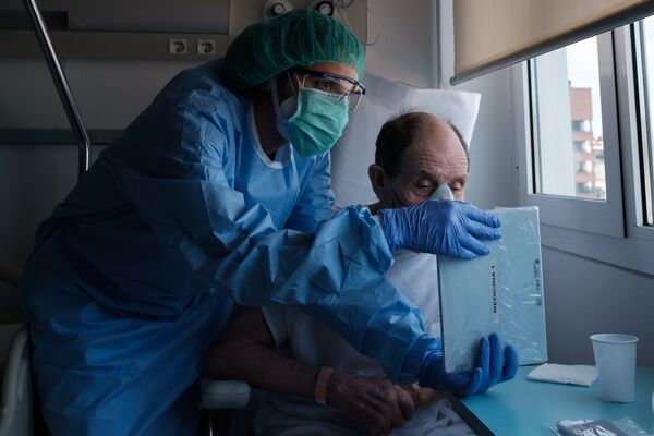 Los pacientes de los hospitales de COVID-19 solo pueden ver a sus seres queridos en las pantallas de sus smartphones. En esta foto de Carles Ramos, titulada Video calls (Videollamadas), una enfermera le muestra una tableta a un paciente. La conmovedora instantánea ganó en la categoría Tecnologías. - Sputnik Mundo