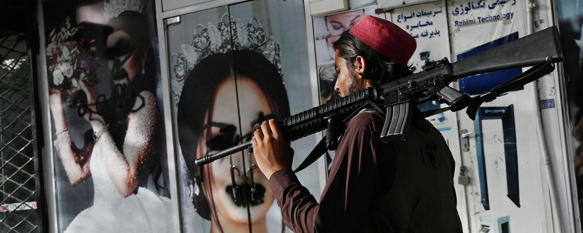 Un soldado talibán camina frente a un salón de belleza con imágenes de mujeres desfiguradas con spray, en Shar-e-Naw en Kabul, el 18 de agosto de 2021 - Sputnik Mundo, 1920, 18.08.2021