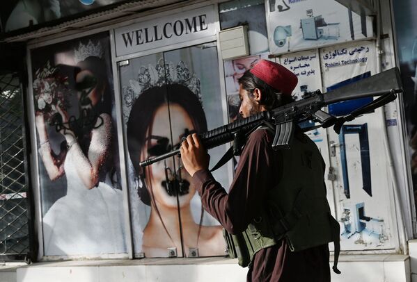 Un talibán (miembro de la organización terrorista Talibán, proscrita en Rusia y otros países) pasa frente a un salón de belleza en Kabul, Afganistán. - Sputnik Mundo