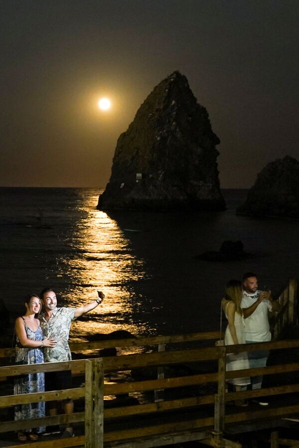 Llamada luna azul &#x27;estacional&#x27;, aparece solo una vez cada tres años aproximadamente.En la foto: la luna de esturión se ve en el cielo de I Faraglioni di Acitrezza en Catania (Italia). - Sputnik Mundo