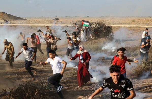 Manifestantes palestinos y periodistas huyen de los soldados israelíes en Gaza. - Sputnik Mundo