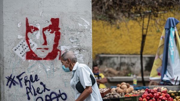 Un hombre camina frente a un graffitti con el rosto de Alex Saab en Caracas, Venezuela - Sputnik Mundo