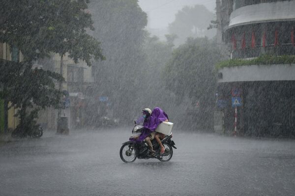 Un motociclista durante las fuertes lluvias en Hanoi, Vietnam. - Sputnik Mundo