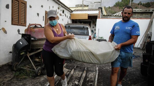 Un hombre y una mujer sacan sus pertenencias de su casa por la actividad del volcán de ‘Cumbre Vieja - Sputnik Mundo