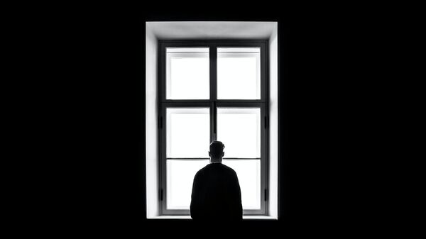 Una persona delante de una ventana en la oscuridad - Sputnik Mundo