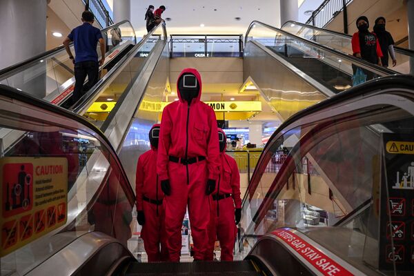 Varias personas vestidas de cosplay como personajes de la serie de televisión El juego del calamar en un centro comercial de Kuala Lumpur, en Malasia. - Sputnik Mundo