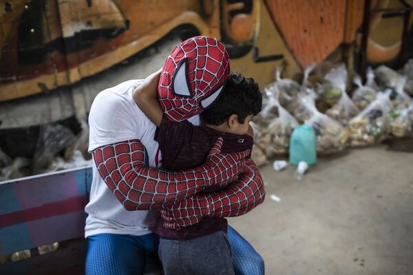 Un voluntario disfrazado de Spiderman abraza a un niño en Río de Janeiro durante una entrega de paquetes de comida organizada por la ONG COVID sin hambre. - Sputnik Mundo