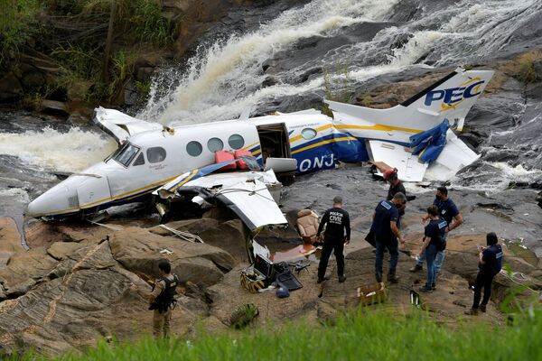 Agentes de Policía revisan los restos de un pequeño avión que se estrelló con la cantante brasileña Marília Mendonça a bordo, cerca de una cascada en Piedade de Caratinga, estado de Minas Gerais (Brasil), el 6 de noviembre de 2021. - Sputnik Mundo