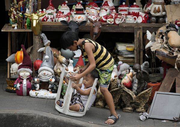 Varios niños juegan cerca de los adornos navideños que se venden en una calle de Manila (Filipinas), el 8 de noviembre de 2021. Muchos filipinos decoran sus hogares, ya que se acerca una de las fiestas más importantes en esta nación predominantemente católica, mientras el Gobierno sigue suavizando las restricciones para frenar la propagación del COVID-19. - Sputnik Mundo