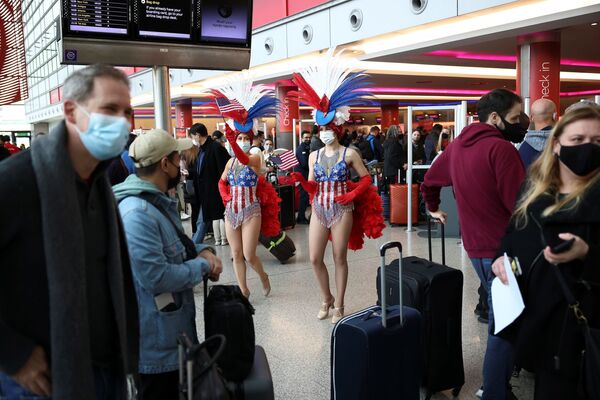 Unos artistas contratados interactúan entre los viajeros que hacen cola para registrarse para los vuelos de Virgin Atlantic y Delta Air Lines en la Terminal 3 del aeropuerto de Heathrow, tras el levantamiento de las restricciones a la entrada de ciudadanos no estadounidenses a EEUU impuestas para frenar la propagación del coronavirus, en Londres (Reino Unido), el 8 de noviembre de 2021. - Sputnik Mundo