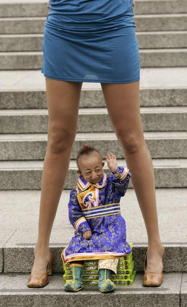 El chino He Pingping, el hombre más pequeño del mundo con 74,61 centímetros, posa con la rusa Svetlana Pankratova, la mujer con las piernas más largas del planeta (132 centímetros). - Sputnik Mundo