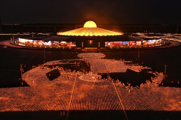 Monjes y devotos budistas encienden 330.000 velas en un intento por romper el récord mundial de la imagen en llamas más grande del mundo durante las celebraciones del Día de la Tierra en el templo budista Wat Dhammakaya en las afueras de Bangkok (Tailandia) el 22 de abril de 2021. - Sputnik Mundo