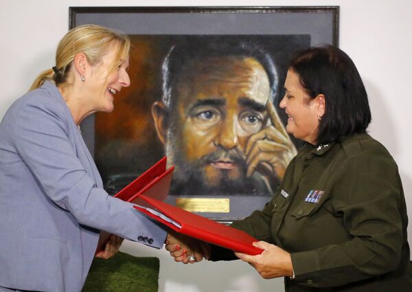 Marie Claude Arsenault, de la policía de Canadá, y Idais Borges Barrios, de la Policía Nacional Revolucionaria de Cuba, estrechan manos con un retrato de Fidel Castro de fondo en La Habana, el 15 de agosto de 2018. - Sputnik Mundo