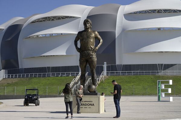 Personas posan para fotos junto a la estatua de Maradona fuera del Estadio Único Madre de Ciudades en Santiago del Estero (Argentina), el 4 de junio de 2021. - Sputnik Mundo