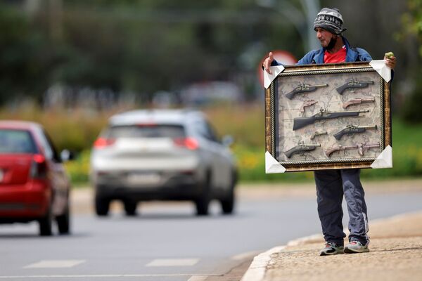 Un migrante colombiano intenta vender réplicas de armas antiguas en una calle de Brasilia (Brasil). - Sputnik Mundo