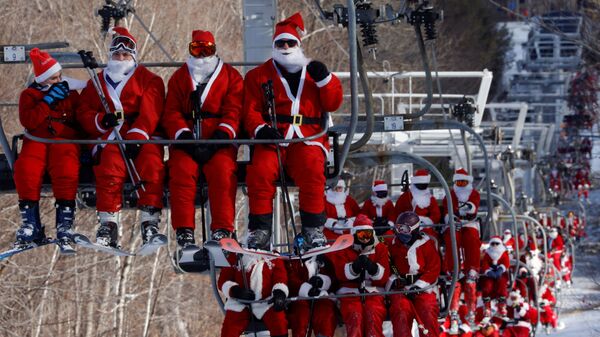 Лыжники в костюмах Санта-Клауса едут на подъемниках, чтобы принять участие в  в Вефиле, штат Мэн, США  - Sputnik Mundo