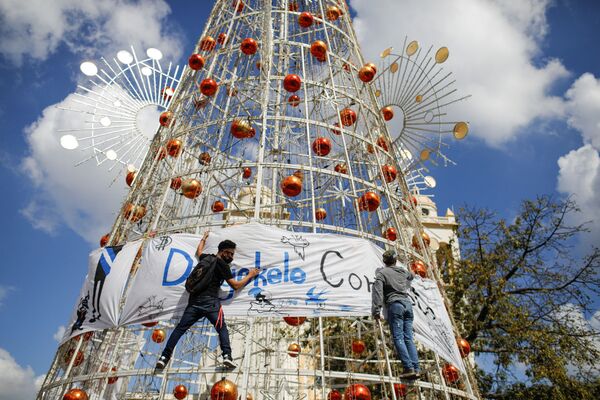 Varios activistas cuelgan una pancarta en un árbol de Navidad en San Salvador durante una protesta contra las políticas del presidente Nayib Bukele. - Sputnik Mundo