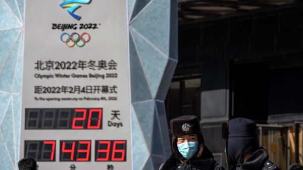 Policía con máscaras para protegerse del COVID-19 pasan junto a un reloj que cuenta el tiempo que falta para la ceremonia de apertura de los Juegos Olímpicos de Invierno de 2022 en Pekín - Sputnik Mundo