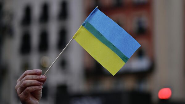 Un manifestante de España con la bandera de Ucrania en la mano - Sputnik Mundo