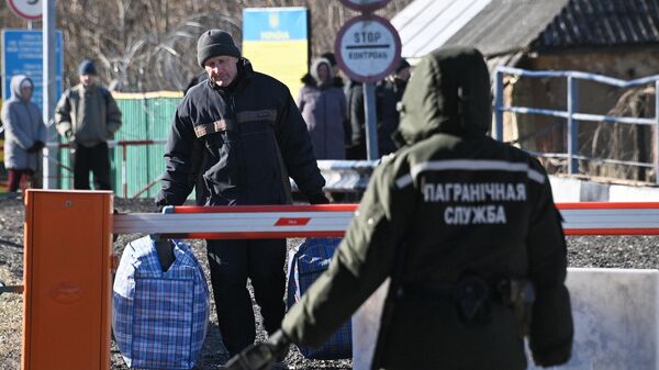 Un hombre ayuda a llevar las cosas a la frontera a una mujer que decidió trasladarse de Ucrania a Bielorrusia - Sputnik Mundo