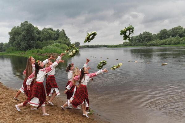 Unas chicas de la aldea de Parichi en Bielorrusia arrojan coronas de flores al río Berezina el día de Iván Kupala, una antigua fiesta pagana de los eslavos orientales que marca el solsticio de verano. - Sputnik Mundo