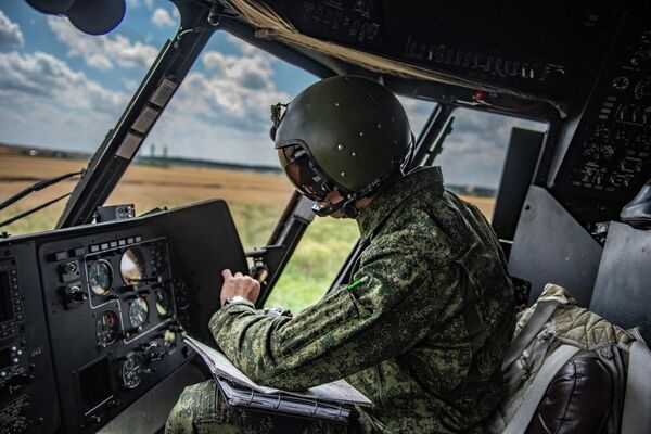 Los pilotos de helicópteros militares rusos protegen convoyes, proporcionan apoyo de fuego en el campo de batalla y apoyo logístico. En la foto: un piloto militar en la cabina de un helicóptero Mi-8MTV en un aeródromo de campo en la zona de la operación militar especial.
 - Sputnik Mundo