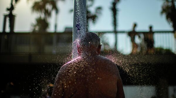 Un hombre se ducha en una playa barcelonesa  - Sputnik Mundo