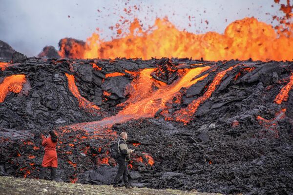 Las personas miran la lava que fluye en el volcán Fagradalsfjall, en Islandia, que se encuentra a 32 kilómetros al suroeste de la capital de Reykjavik y cerca del aeropuerto internacional de Keflavik. Las autoridades de Islandia afirman que el volcán entró en erupción solo ocho meses después de que su última erupción haya terminado oficialmente. - Sputnik Mundo
