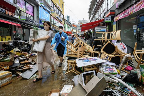 Varias personas pasan junto a los escombros que se amontonaron afuera de las tiendas del histórico mercado de Namseong, en Seúl, después de las inundaciones por las lluvias. - Sputnik Mundo