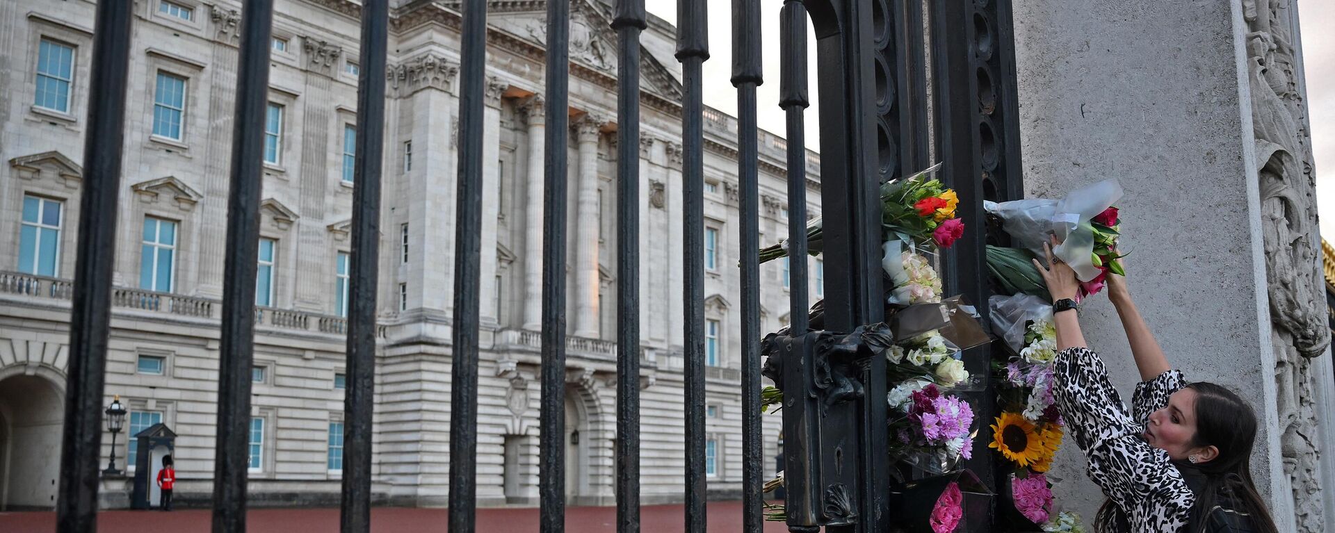 Una mujer deposita unas flores en el exterior del Palacio de Buckingham, en el centro de Londres, tras anunciarse la muerte de la reina Isabel II - Sputnik Mundo, 1920, 08.09.2022
