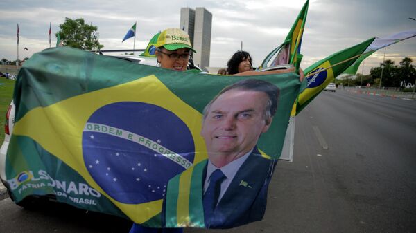 Una mujer sostiene una bandera con la imagen del presidente de Brasil, Jair Bolsonaro en las elecciones presidenciales - Sputnik Mundo