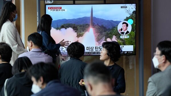 Un grupo de personas observa un programa de noticias que muestra una imagen de archivo del lanzamiento de un misil por parte de Corea del Norte - Sputnik Mundo