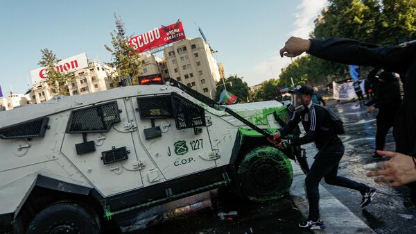 Протестующий атакует полицейский броневик в Сантьяго-де-Чили в третью годовщину масштабных протестов против повышения цен на коммунальные услуги - Sputnik Mundo