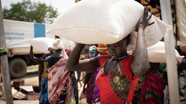 Mujeres llevan bolsas de sorgo durante una distribución de alimentos del Programa Mundial de Alimentos (PMA) de las Naciones Unidas en Gumuruk, Sudán del Sur - Sputnik Mundo