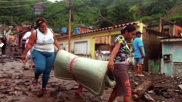 Жители Пуэрто-ла-Крус, Венесуэла, выносят из разрушенных оползнем домов уцелевшие вещи - Sputnik Mundo