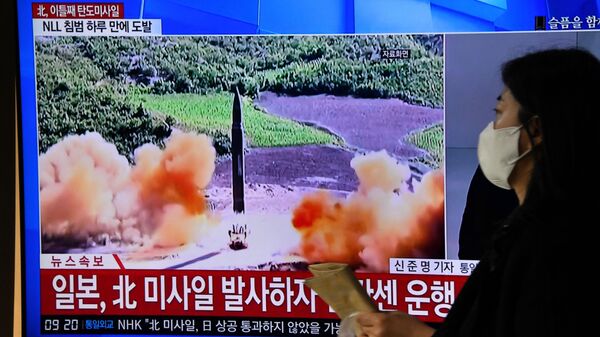 Una mujer pasa junto a una pantalla de televisión que muestra un noticiero con imágenes de archivo de una prueba de misiles de Corea del Norte, en una estación de tren en Seúl el 3 de noviembre de 2022. - Sputnik Mundo