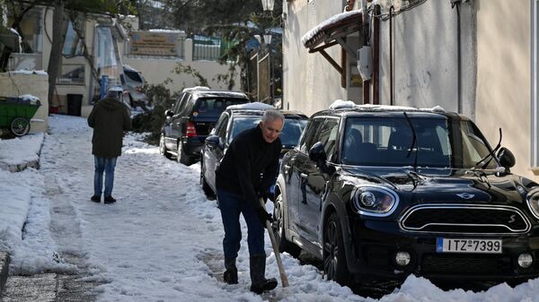 Un hombre arrastra nieve en una calle de Atenas, Grecia  - Sputnik Mundo