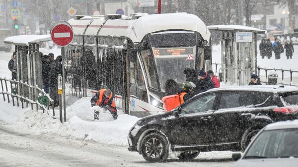 Работник коммунальной службы очищает от снега остановку городского транспорта в Москве - Sputnik Mundo