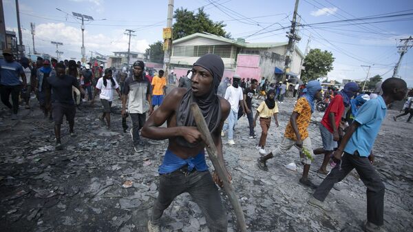 Un manifestante en Haití porta un trozo de madera que simula un arma durante una protesta que exige la dimisión del primer ministro, Ariel Henry - Sputnik Mundo