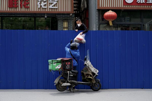 Durante un nuevo confinamiento por COVID-19 en Pekín es captado un repartidor de objetos por aplicación para asistir a una persona cercada en un área residencial. 11 de mayo.  - Sputnik Mundo