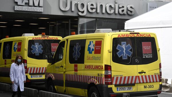 Una trabajadora sanitaria pasa junto a las ambulancias frente al hospital La Paz de Madrid  - Sputnik Mundo
