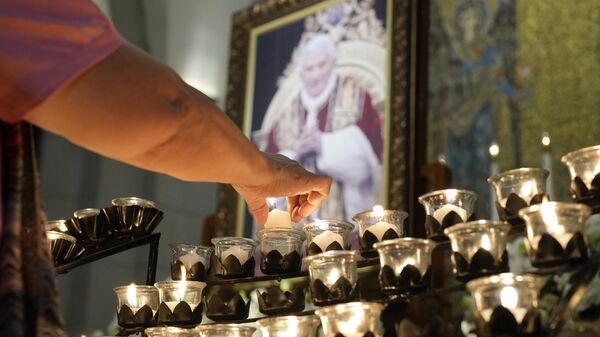 Una vela ante el retrato del difunto Papa emérito Benedicto XVI  - Sputnik Mundo