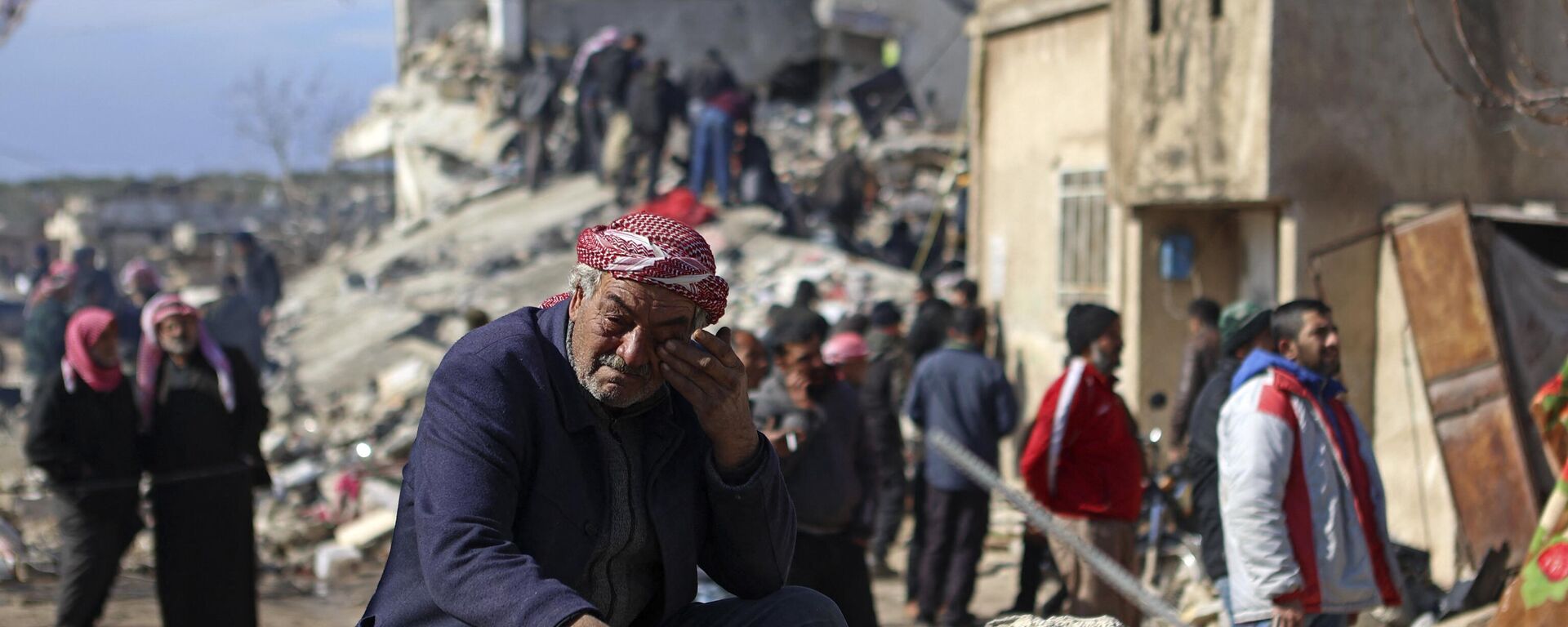 Un hombre sirio llora sentado sobre los escombros de un edificio derrumbado en la ciudad de Jindayris, controlada por los rebeldes, el 7 de febrero de 2023, tras un terremoto mortal.  - Sputnik Mundo, 1920, 07.02.2023