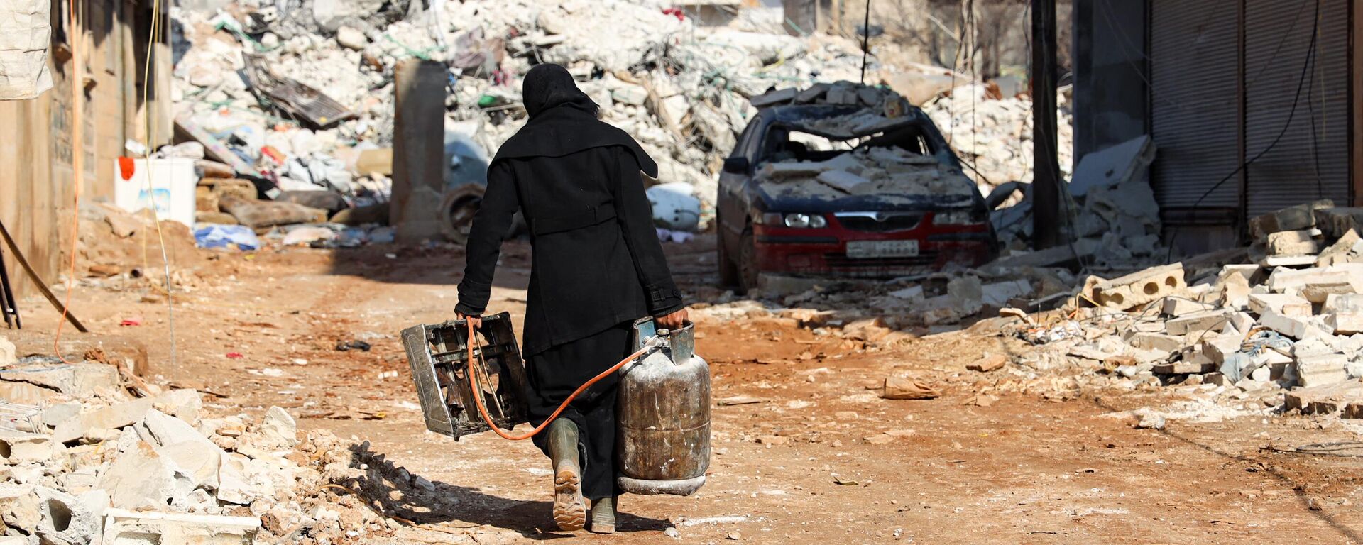 Mujer rescata una pequeña estufa y una bombona de gas, en la ciudad siria de Jindayris, Alepo controlada por los rebeldes, el 10 de febrero de 2023  - Sputnik Mundo, 1920, 12.02.2023