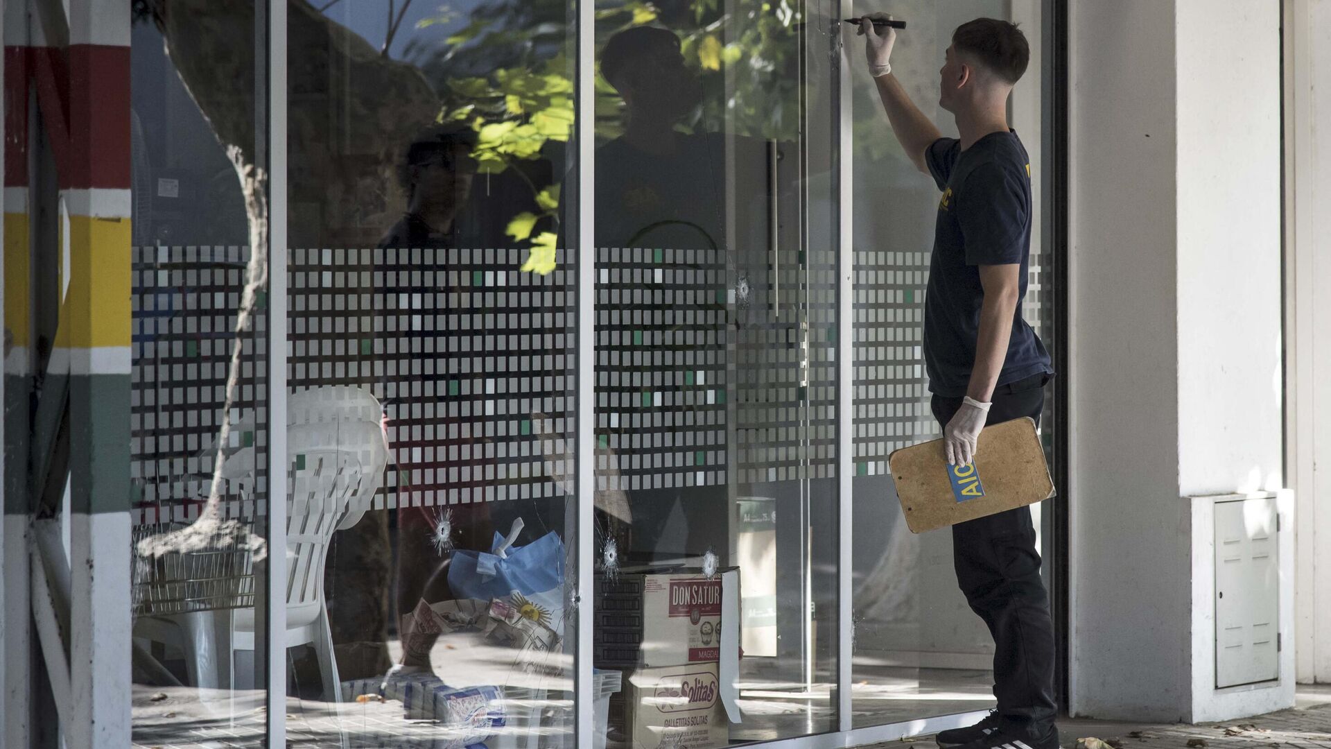 Un agente de policía inspecciona los agujeros de bala en una ventana de un supermercado perteneciente a la familia de Antonela Roccuzzo, la esposa de Lionel Messi, en Rosario, provincia de Santa Fe, Argentina, el 2 de marzo de 2023 - Sputnik Mundo, 1920, 02.03.2023