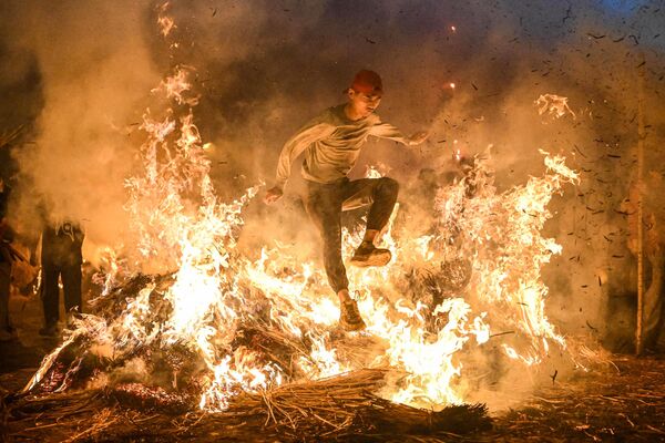 Un residente de la provincia china de Guangdong salta sobre una hoguera para atraer la buena suerte, durante una fiesta local. - Sputnik Mundo